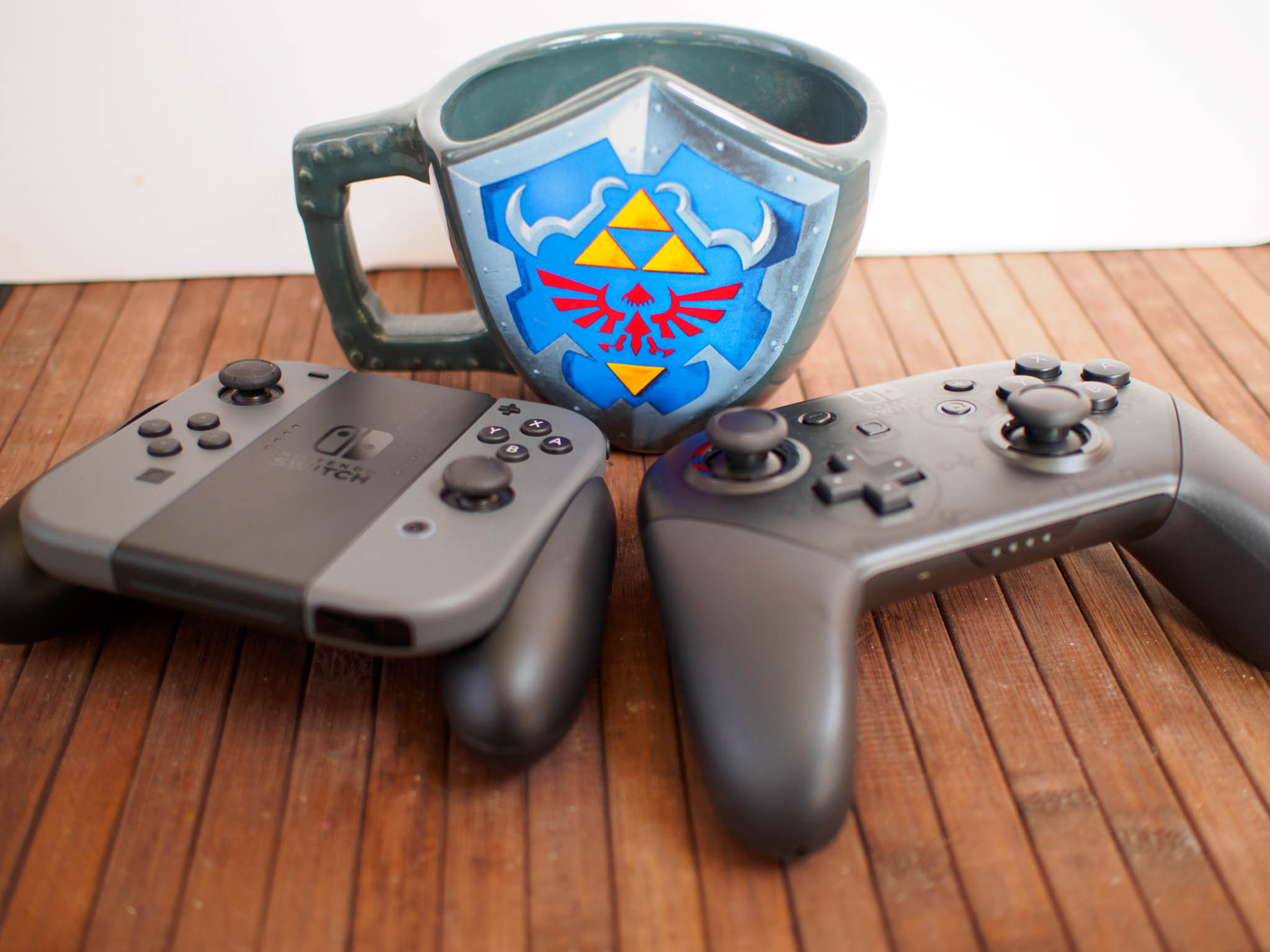Joy-Con next to a Pro Controller with a Zelda mug between them