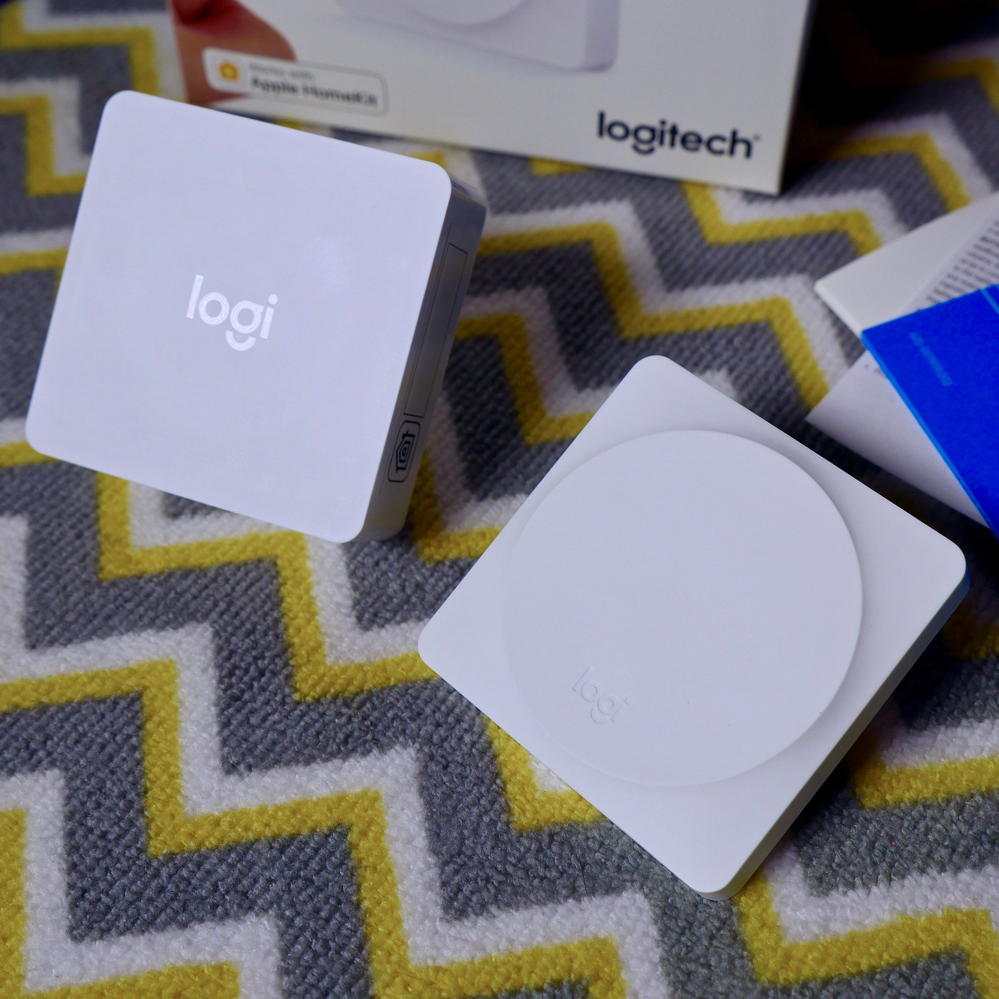 The Logitech POP Smart Button sits beside the HomeKit-enabled POP bridge, a startup guide, and the box in which everything came.