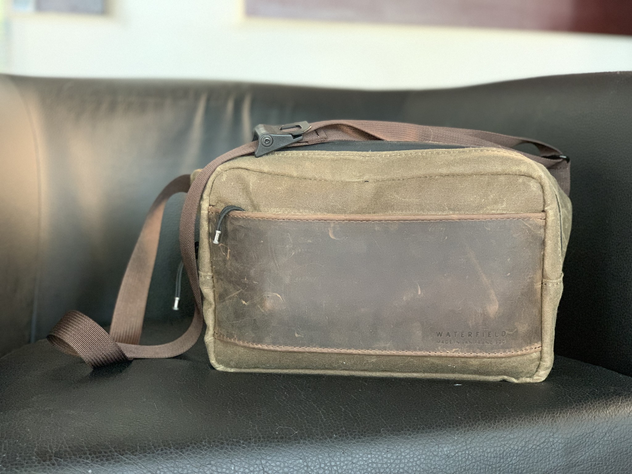 Waterfield Designs Sutter Sling Pouch for Nintendo Switch sitting on a black leather chair
