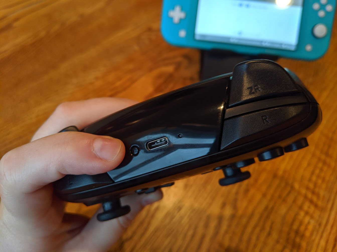 How to pair Pro Controllers to Nintendo Switch Lite: hold the small button at the top of the controller by the USB-C port for three seconds or until paired