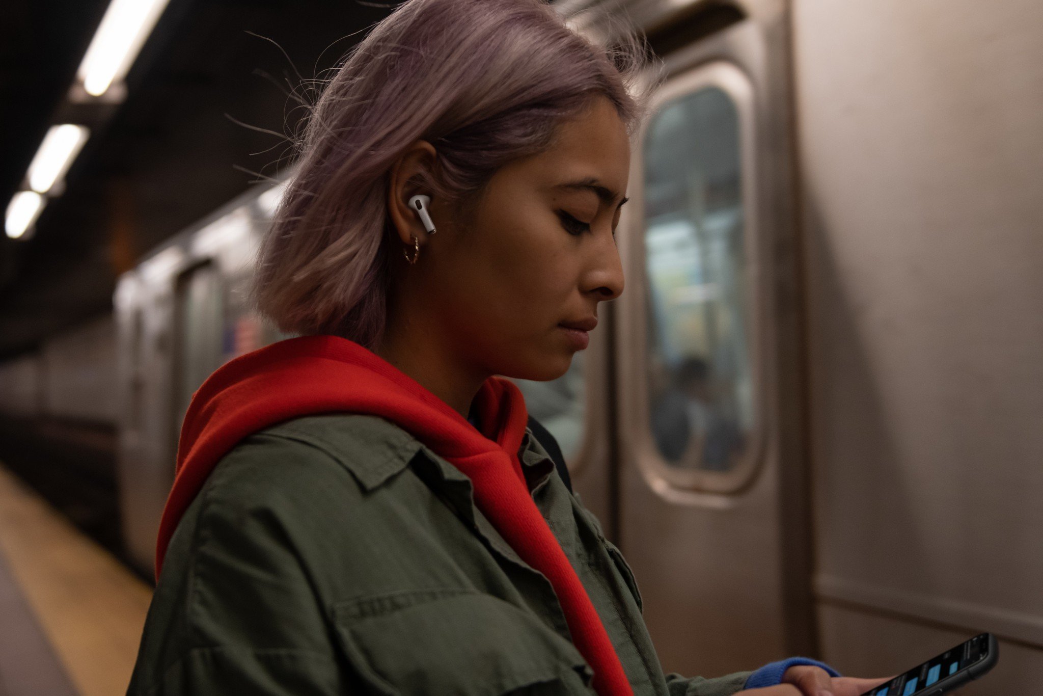 Woman wears AirPods Pro while waiting in train station