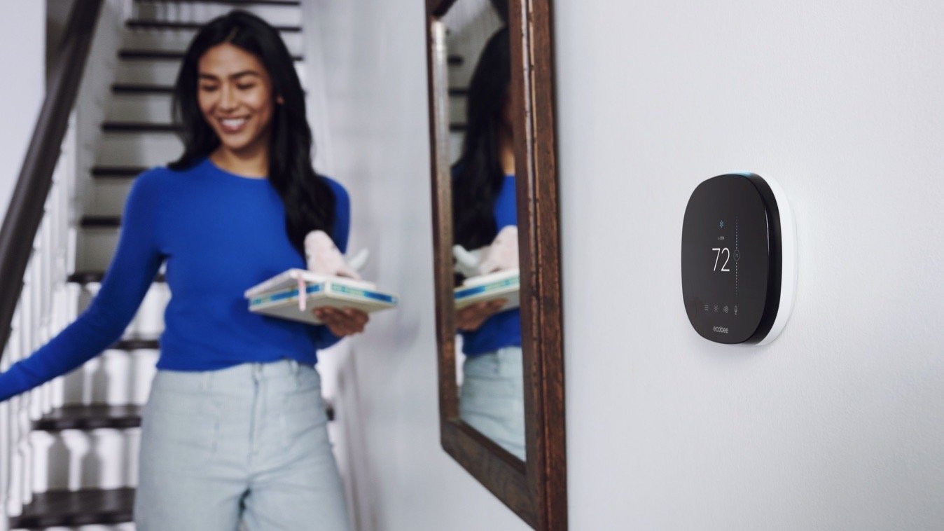 ecobee SmartThermostat on a wall in front of person walking down stairs