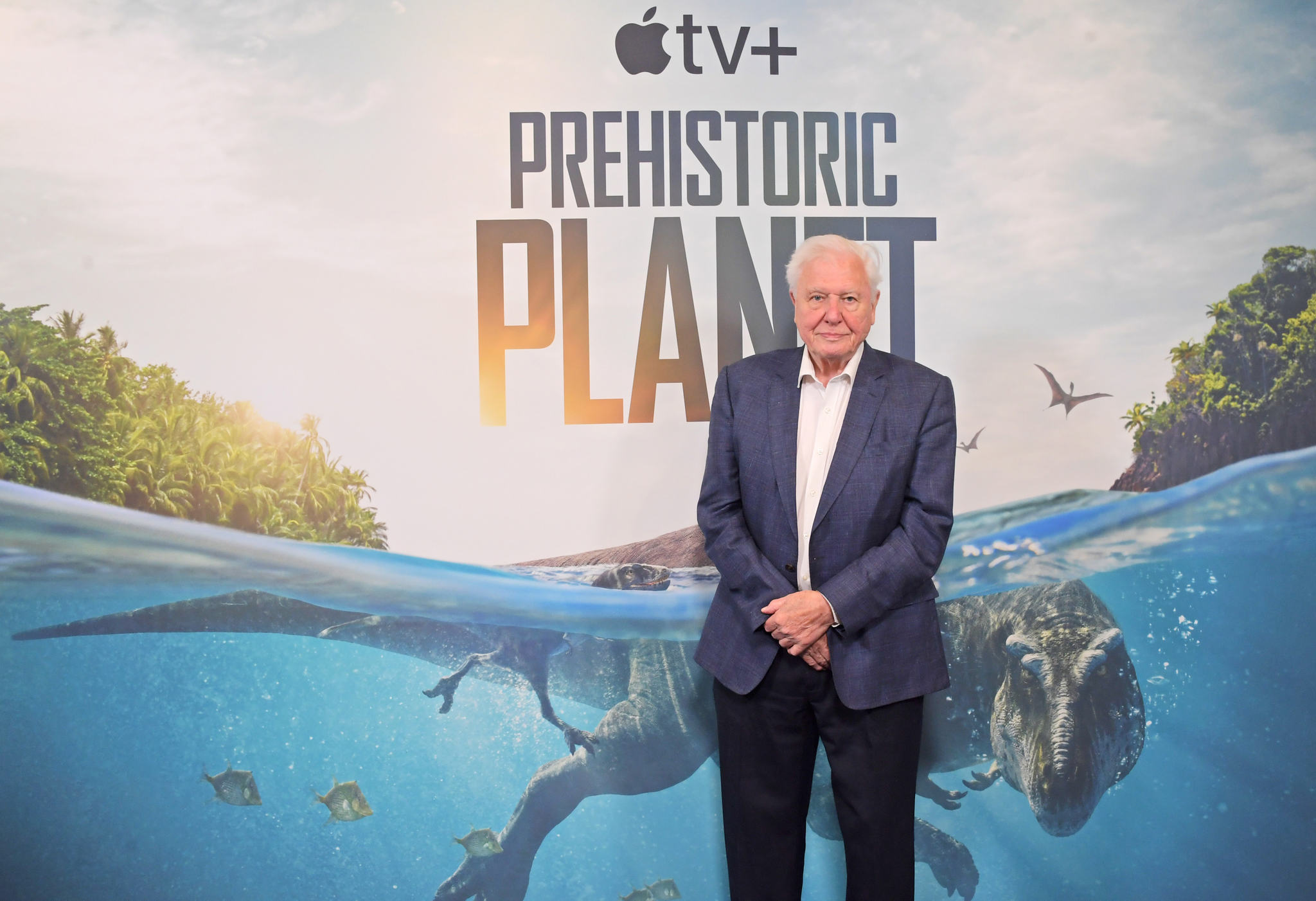 Sir David Attenborough in front of Prehistoric Planet artwork