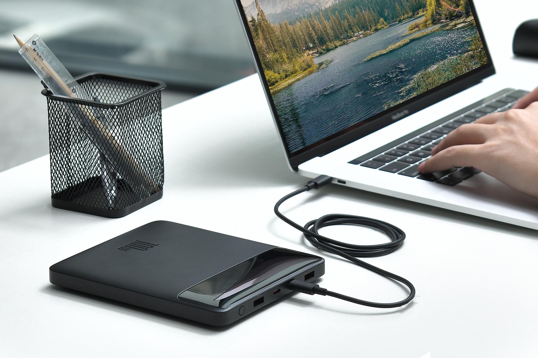 Baseus 100W power bank on desk charging a MacBook
