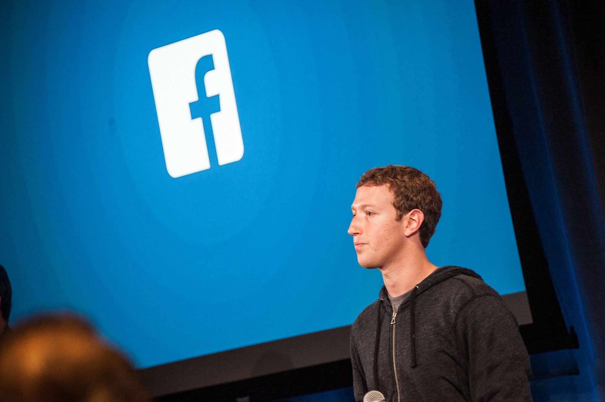Mark Zuckerberg in front of the Facebook logo