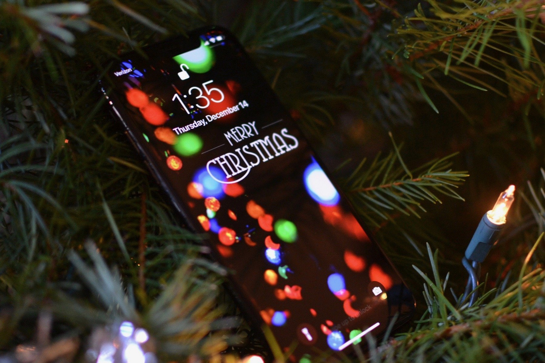 An iPhone with a festive background resting in a Christmas tree