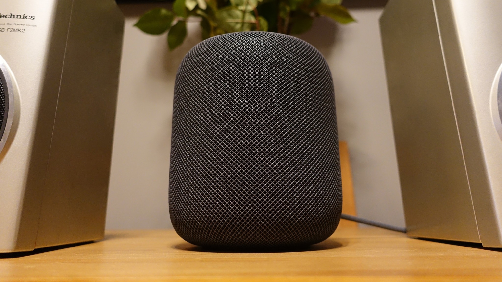 Apple HomePod in Space Gray on a table between two speakers