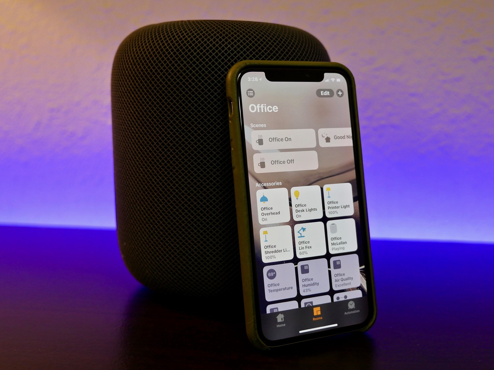 An iPhone X sits in front of a HomePod. The Home app for iOS is open on screen.