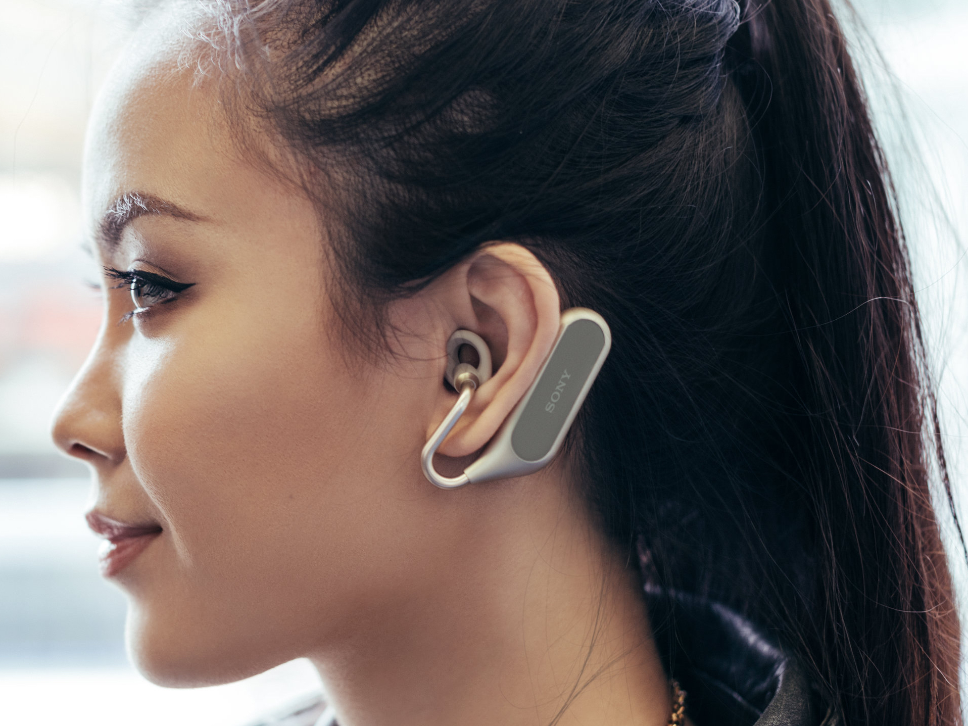 An individual in profile wearing Sony's Xperia Ear Duo wireless earbuds